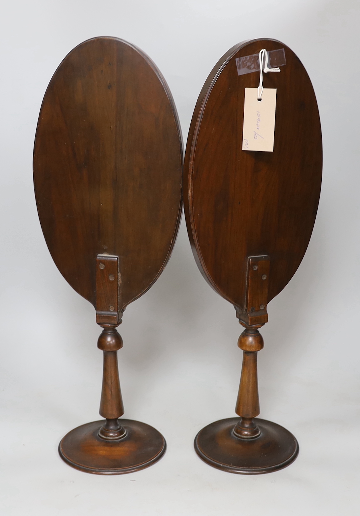 A pair of oval walnut framed shaving mirrors, each 51cm high